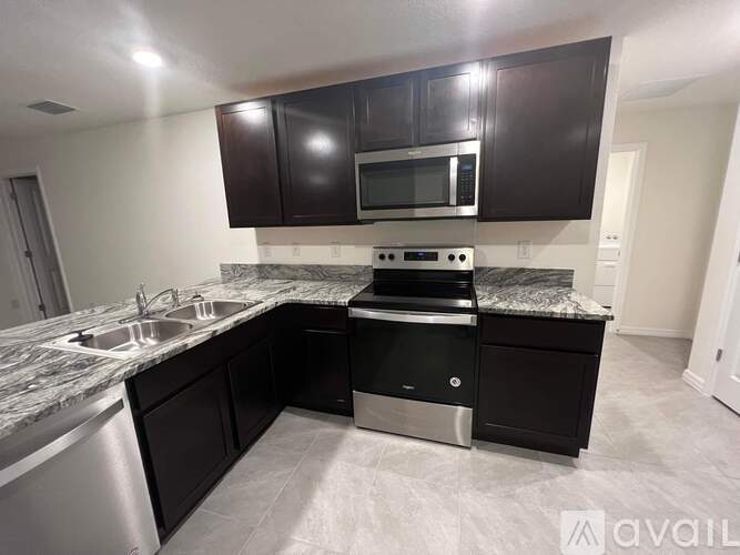 A kitchen with black cabinets and a granite countertop.