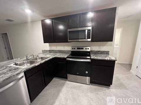 A kitchen with black cabinets and a granite countertop.
