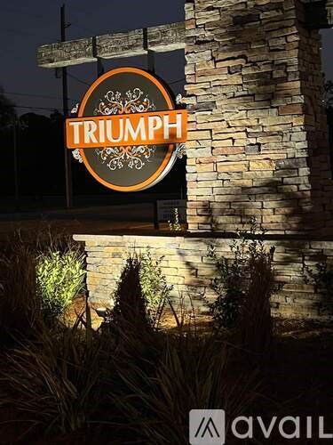A sign that says "TRIUMPH" is hanging from a stone pillar.