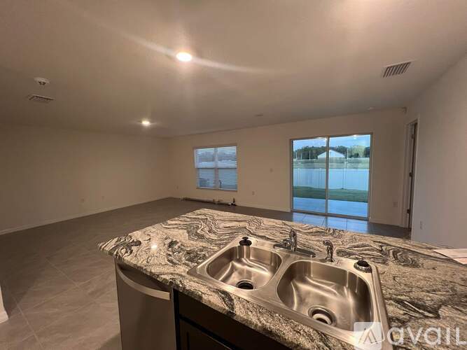 A large, empty room with a marble countertop and a window overlooking a body of water.