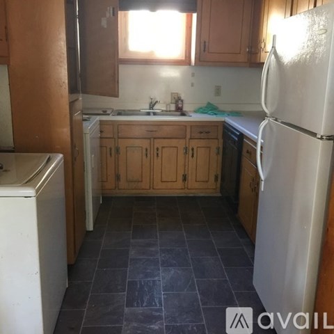 A kitchen with a white refrigerator and wooden cabinets.