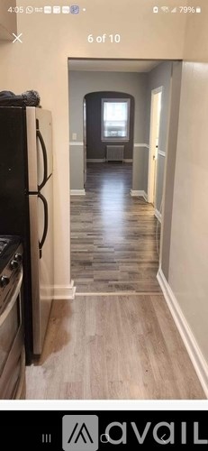 A kitchen with a black fridge and wooden floors.