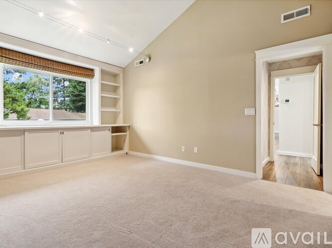 A spacious room with a window and a door leading to another room.