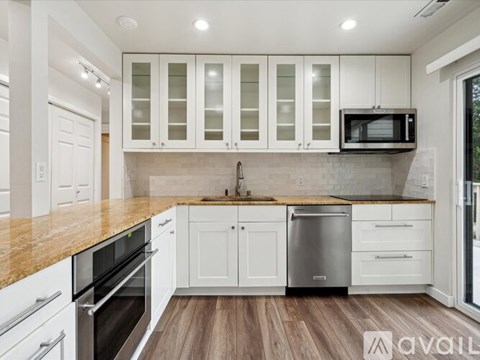 A modern kitchen with white cabinets and stainless steel appliances.