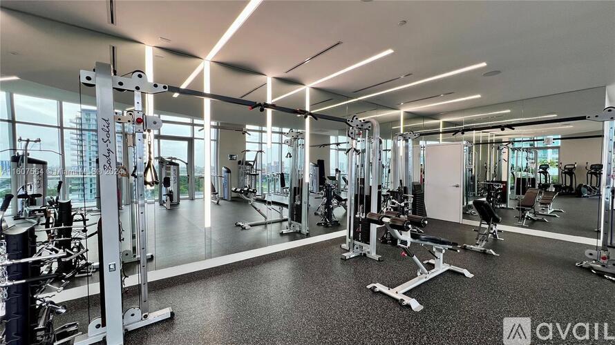 A gym with various exercise equipment and a glass wall.
