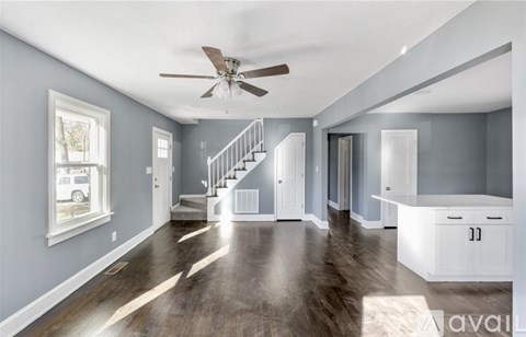 A spacious room with a staircase and a ceiling fan.