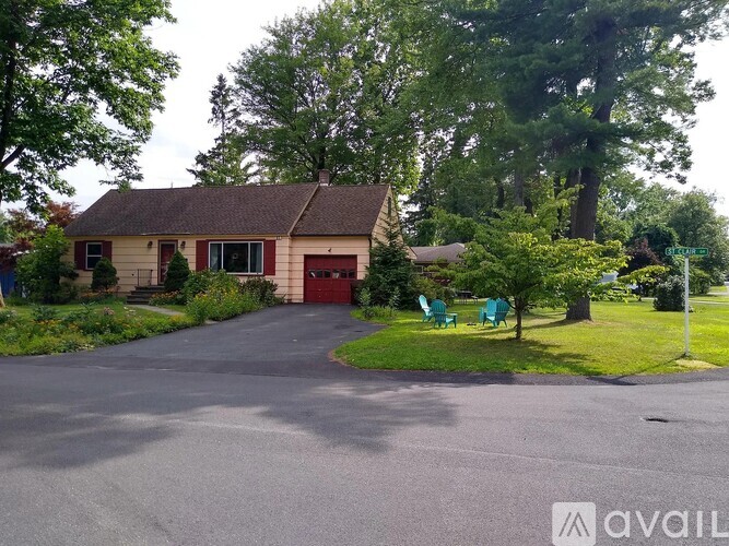 A house with a red door is surrounded by greenery.