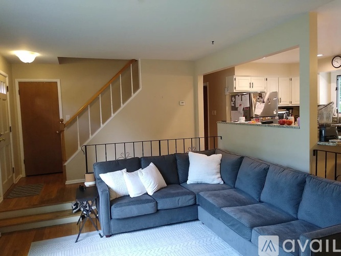 A living room with a grey couch and a staircase in the background.