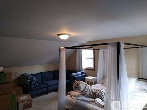 A bedroom with a canopy bed and a blue couch.