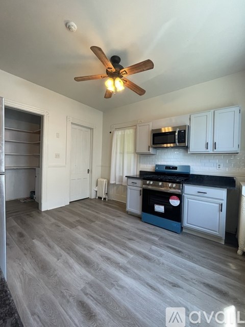 A kitchen with a fan on the ceiling and a microwave above the stove.