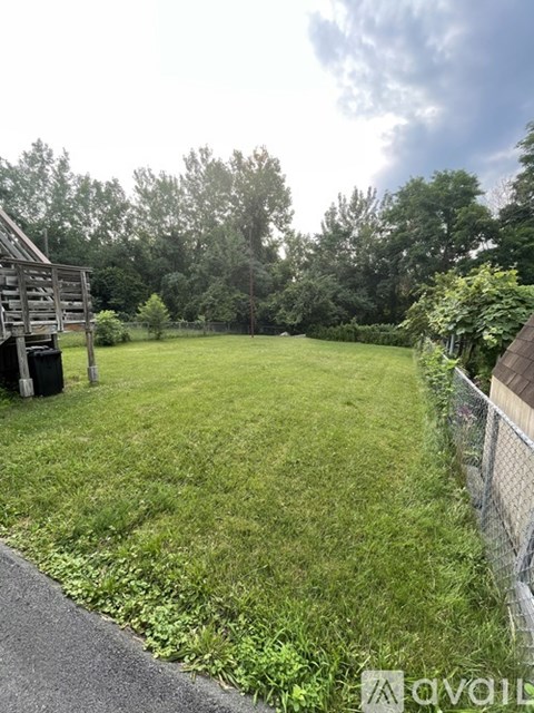 A backyard with a fence, a shed, and a grassy area.
