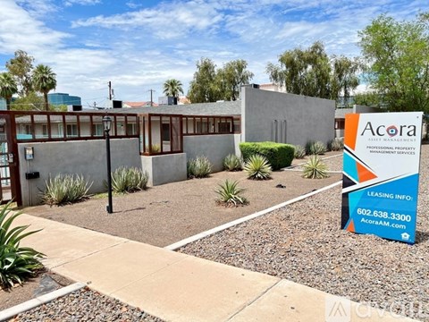 A sign for Acora Professional Property Management Services is in front of a building.