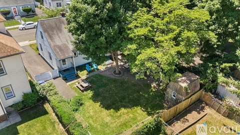 A backyard with a tree, a fence, and a small building.