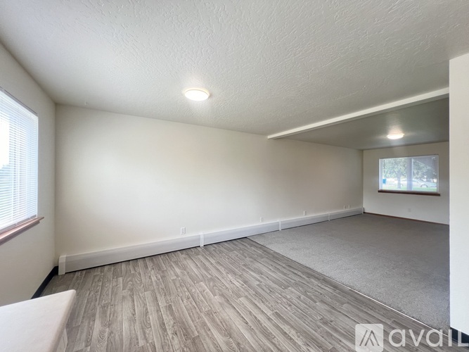 A room with a window and a wooden floor is available for rent.