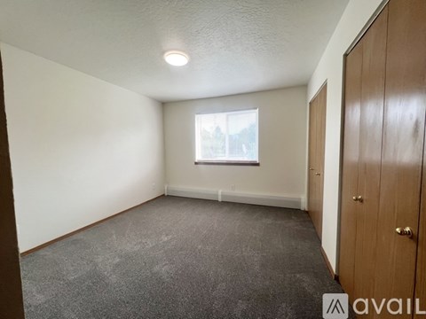A room with a carpeted floor, a window, and a wooden door.
