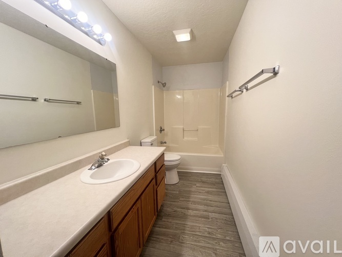 A bathroom with a sink, mirror, toilet, and a light on the wall.