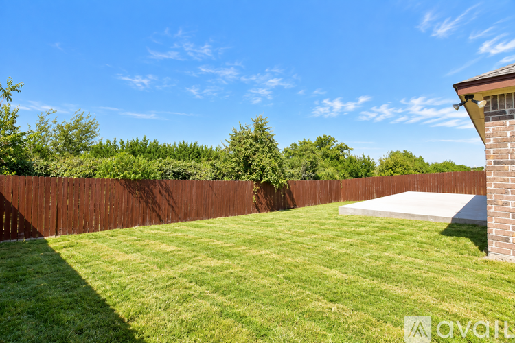 A backyard with a wooden fence and a green lawn.