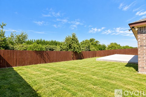 A backyard with a wooden fence and a green lawn.