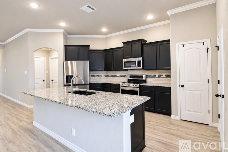A kitchen with black cabinets and a granite countertop.