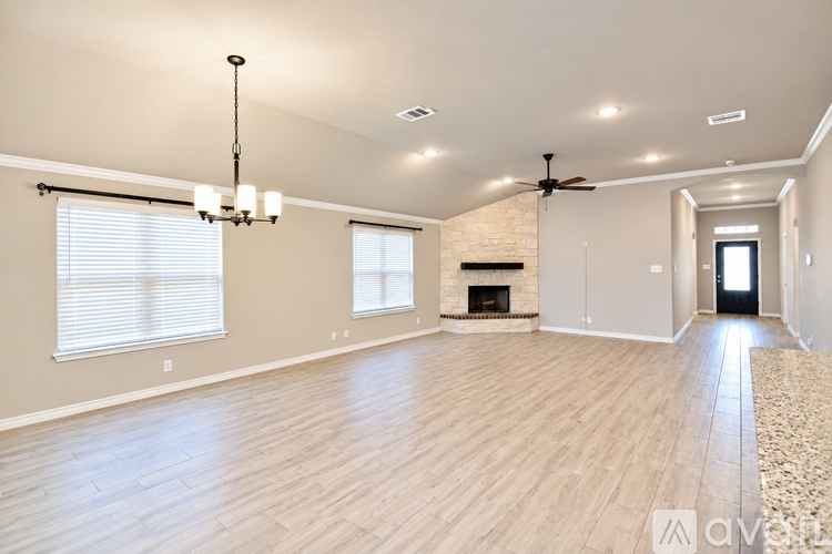 A spacious living room with a fireplace and a chandelier.