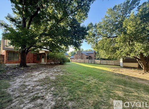 A tree in a yard with a house in the background.