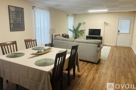 A dining room with a table set for four and a couch in the background.