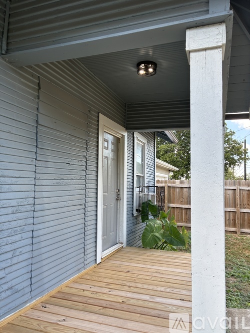 A porch with a white column and a grey door.