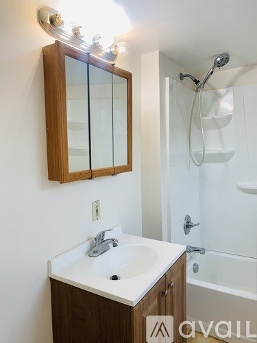 A bathroom with a sink, mirror, and bathtub.
