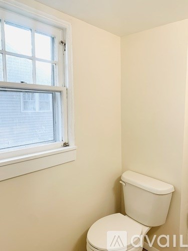 A white toilet in a small room with a window.
