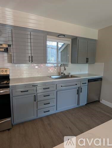 A kitchen with a white countertop and grey cabinets.