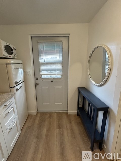 A kitchen with white appliances and a wooden floor.