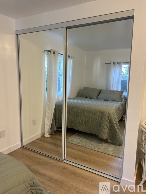 A bedroom with a bed and a mirrored wardrobe.