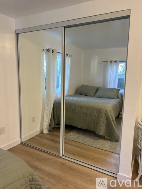 A bedroom with a bed and a mirrored wardrobe.