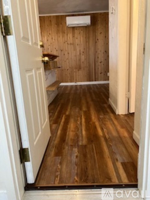 A hallway with wood floors and a white door.