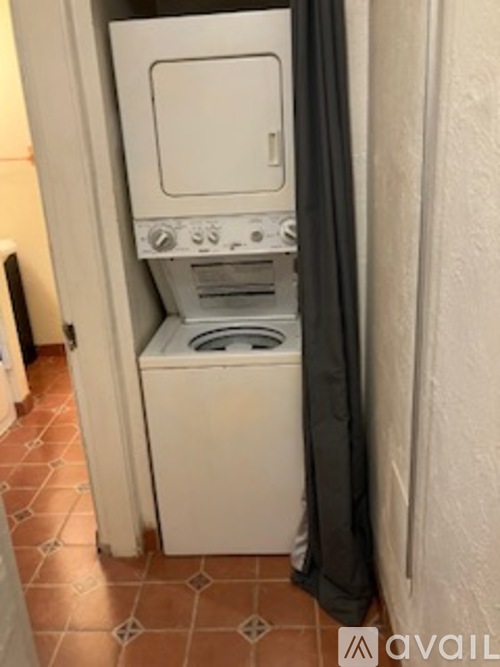 A small white washing machine sits in a narrow space.