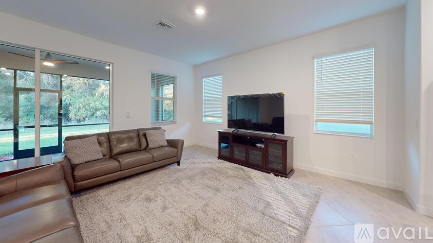 A living room with a brown couch and a television on a wooden stand.