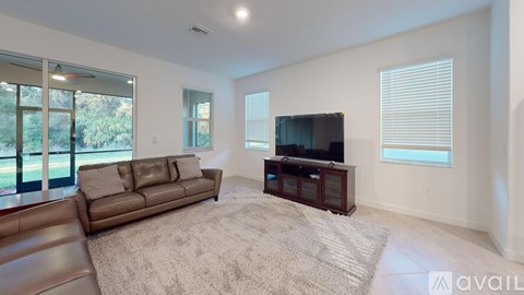 A living room with a brown couch and a television on a wooden stand.