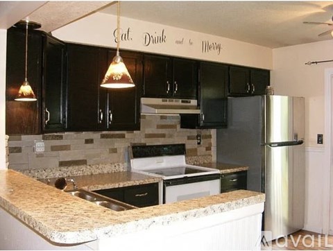 A kitchen with a granite counter top and a sign that says "Eat, Drink and Be Merry".