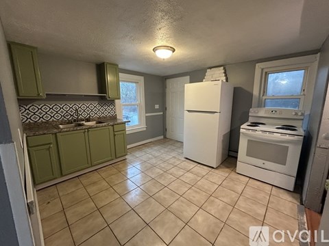 A kitchen with green cabinets and a white fridge.