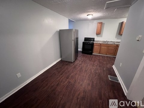 A kitchen with a refrigerator and oven in a room with wood flooring.