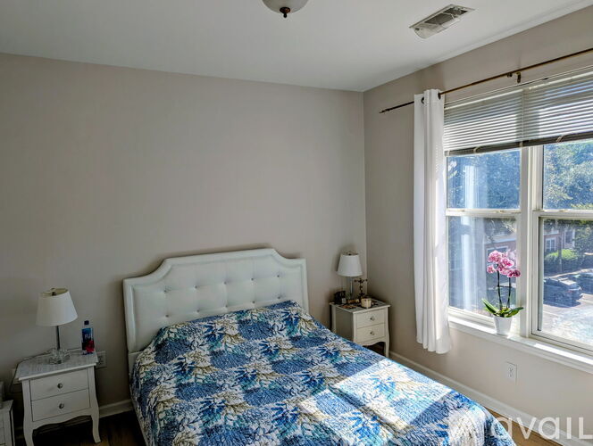 A bedroom with a bed, nightstands, and a window with blinds.