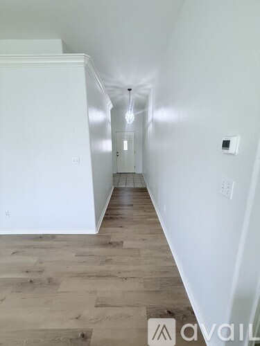 A long hallway with wood floors and white walls.