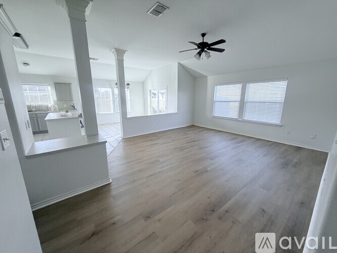 A spacious room with wooden flooring and a ceiling fan.