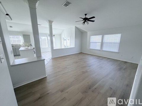 A spacious room with wooden flooring and a ceiling fan.