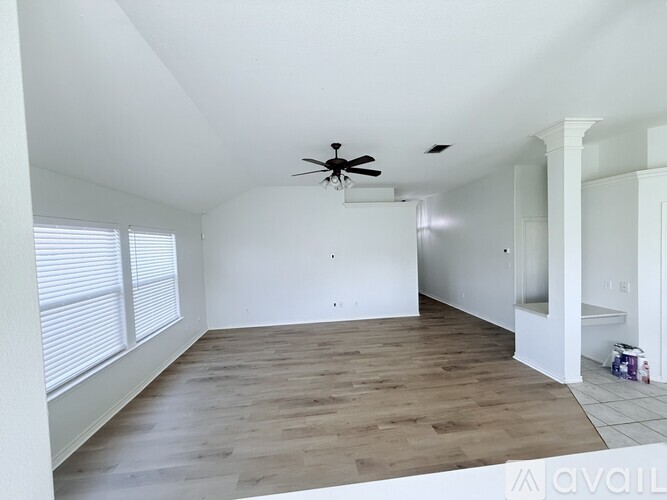A room with a ceiling fan and wooden flooring.