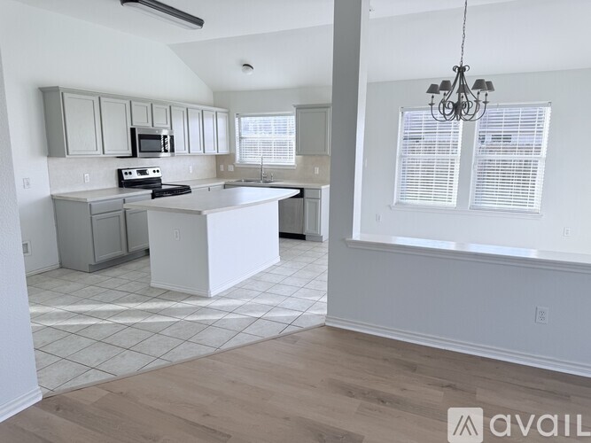 A kitchen with a white island and a chandelier hanging from the ceiling.