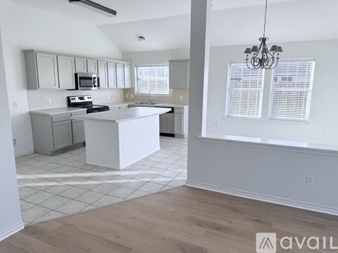 A kitchen with a white island and a chandelier hanging from the ceiling.