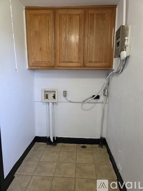 A kitchen with wooden cabinets and a white wall.