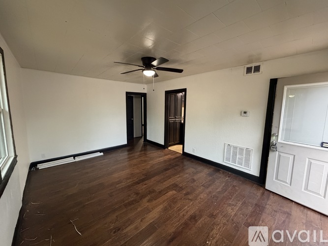 A room with a ceiling fan and wooden flooring.