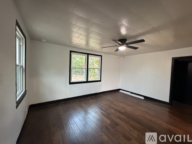 A room with a ceiling fan and wooden flooring.